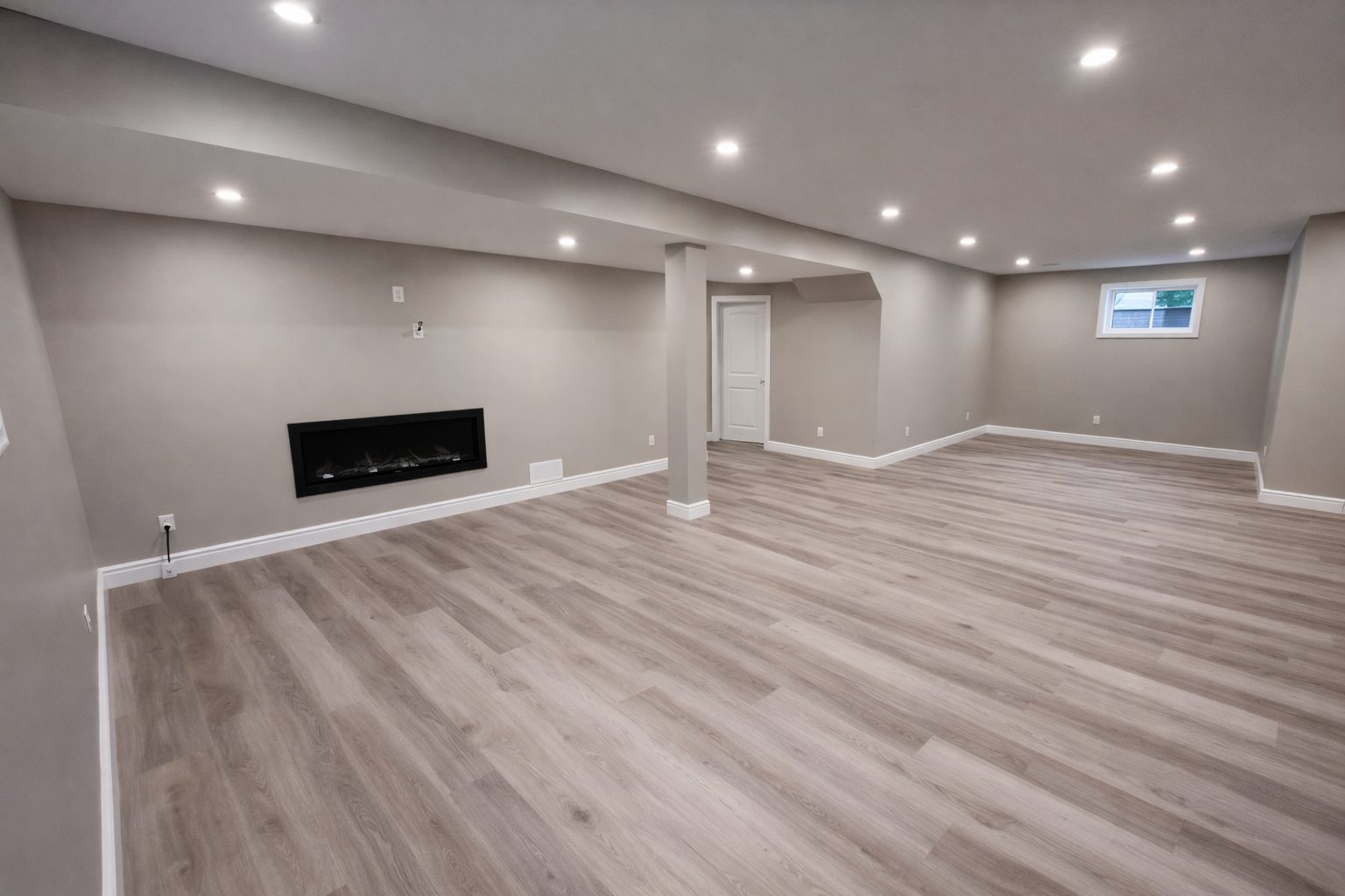 Finished basement with grey LVP flooring and pot lights