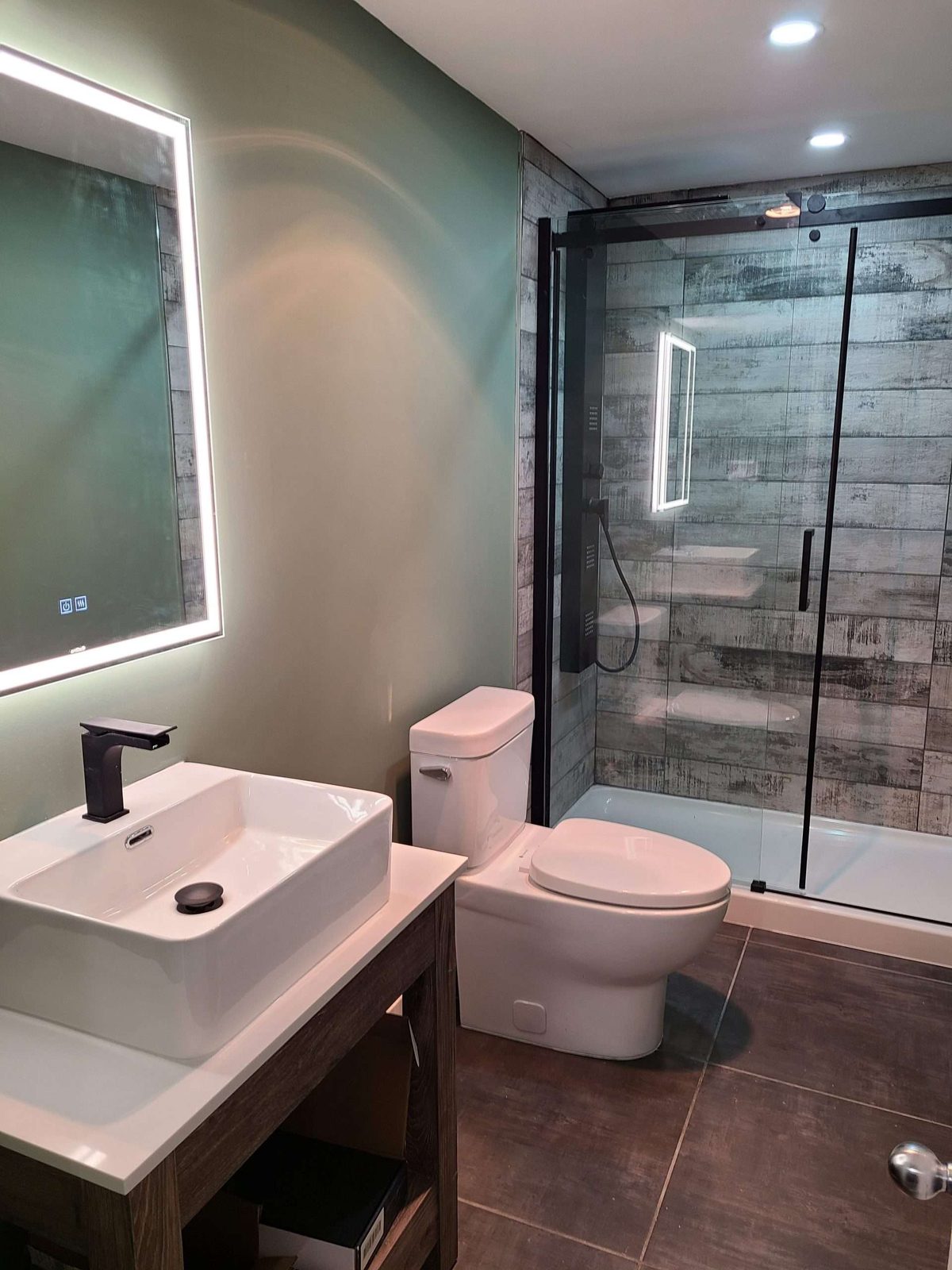 Moody green-wall bathroom with backlit round mirror